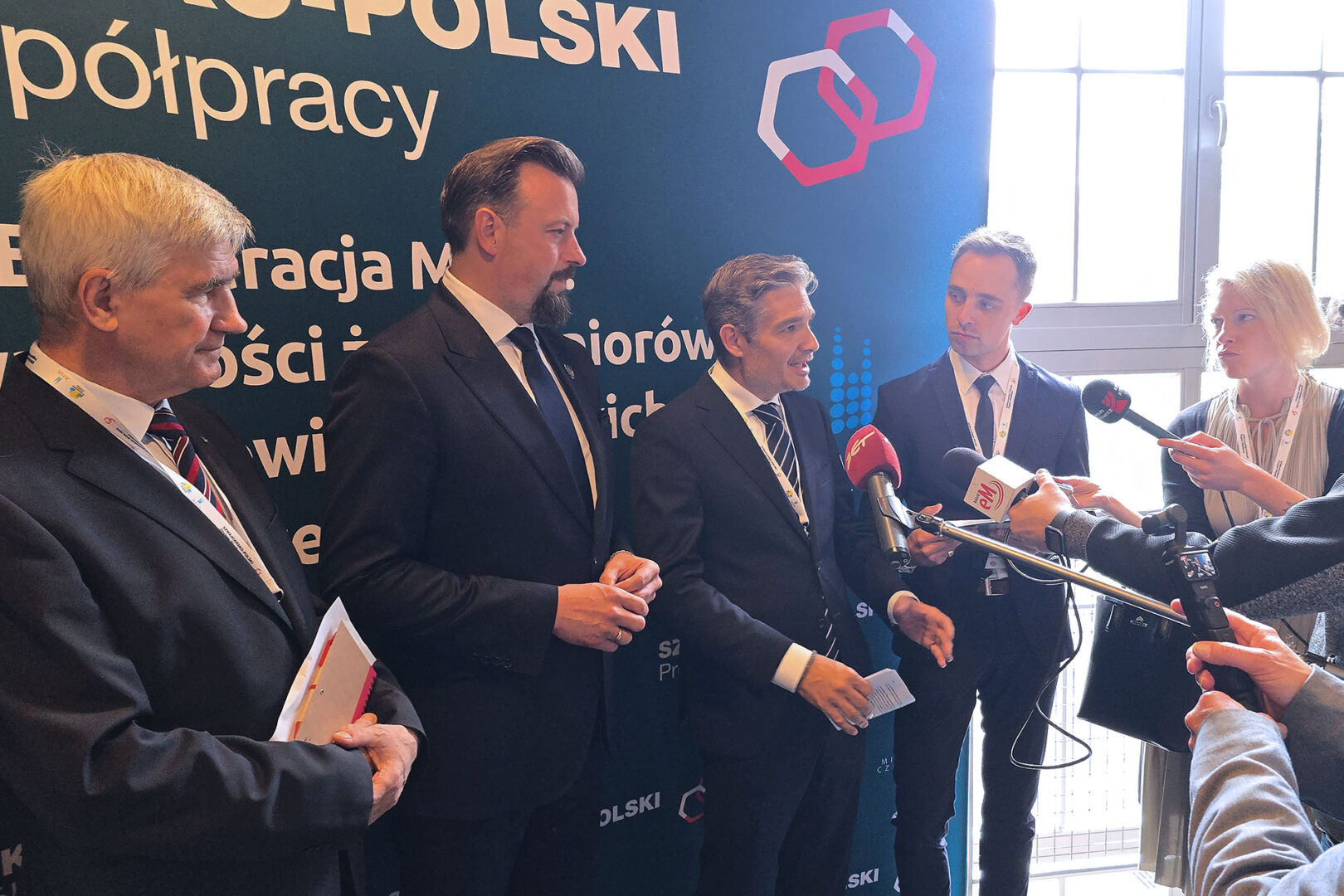 Lokalni politycy udzielają wywiadu na tle ścianki Szwajcarsko-Polskiego Programu Współpracy.
